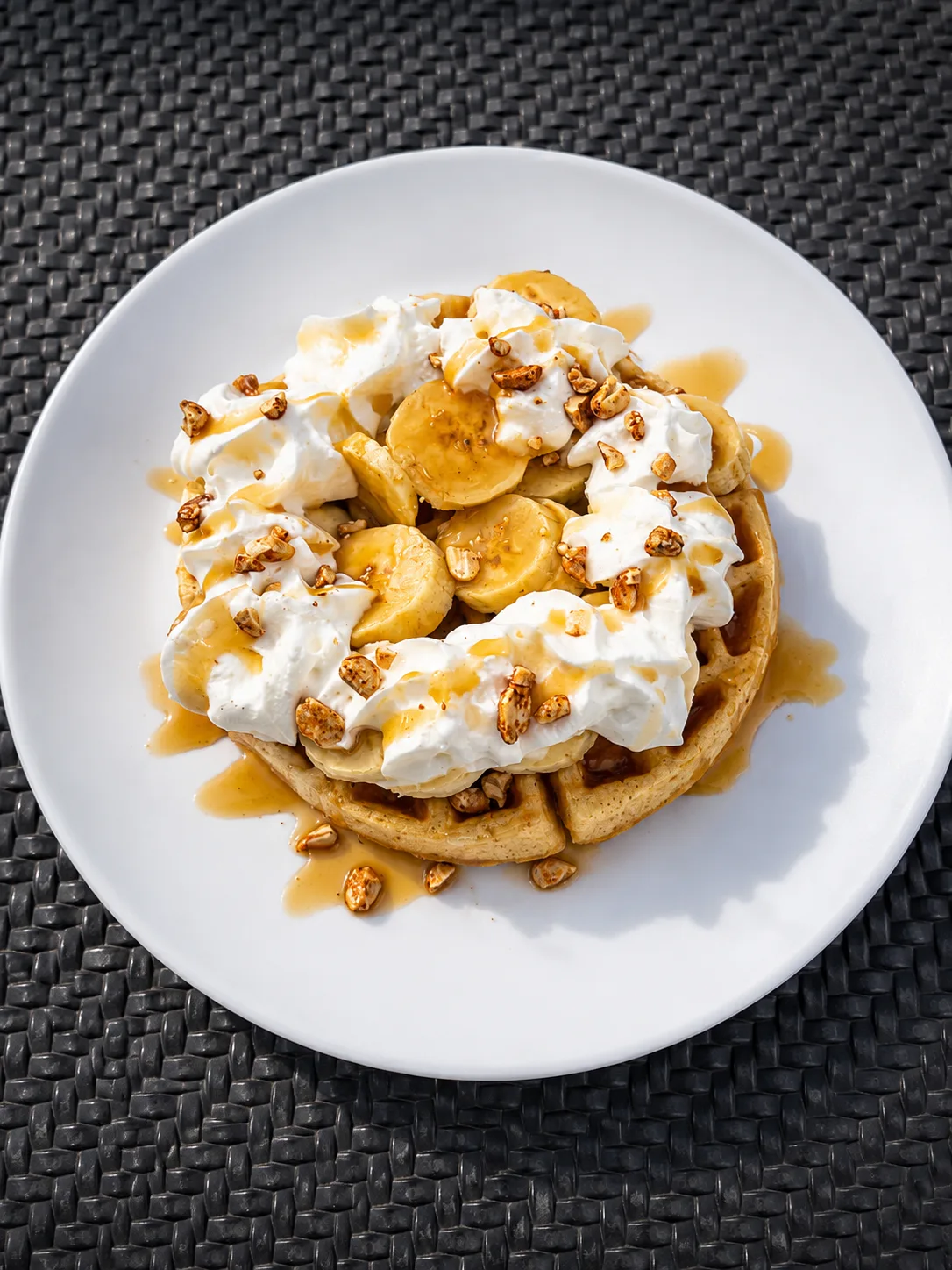 Banoffee waffle topped with banana, whipped cream, caramel and toasted nuts