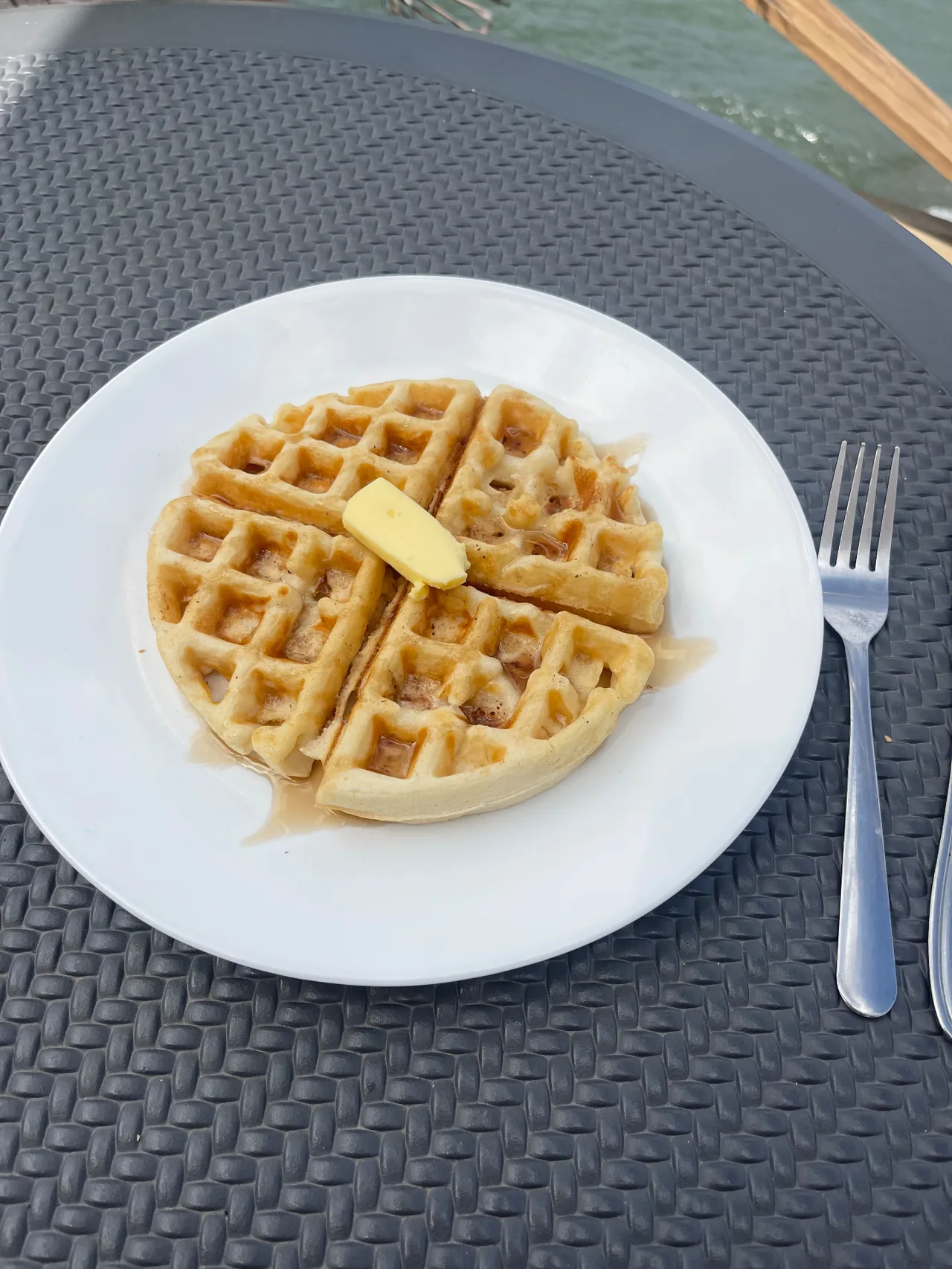 Plain waffle with butter and syrup on a white plate